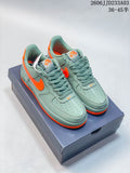 Pair of green Nike Air Force 1 ’07 low-top sneakers with bright orange accents on a shoebox