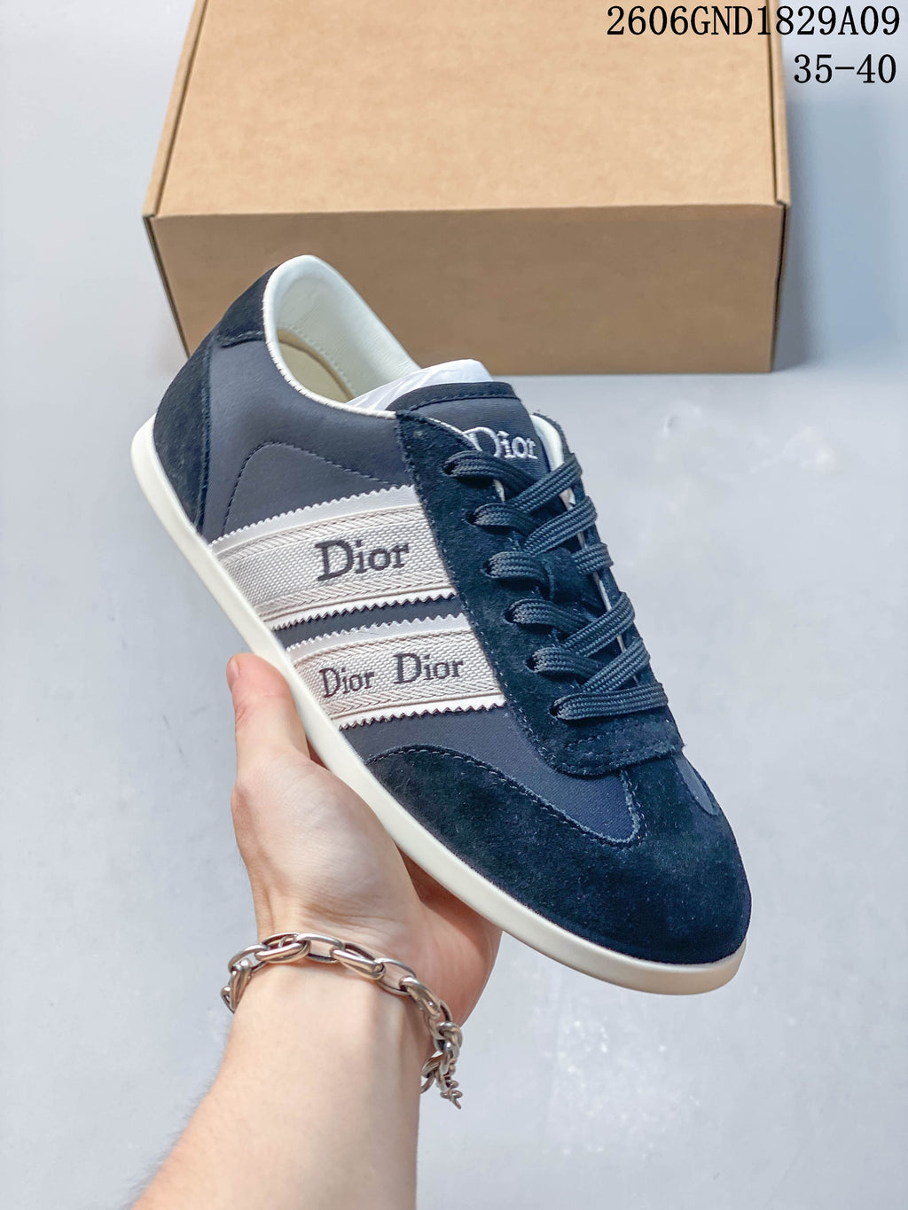 Angled view of a navy low-top sneaker with white ribbon-style side panels and tonal laces.