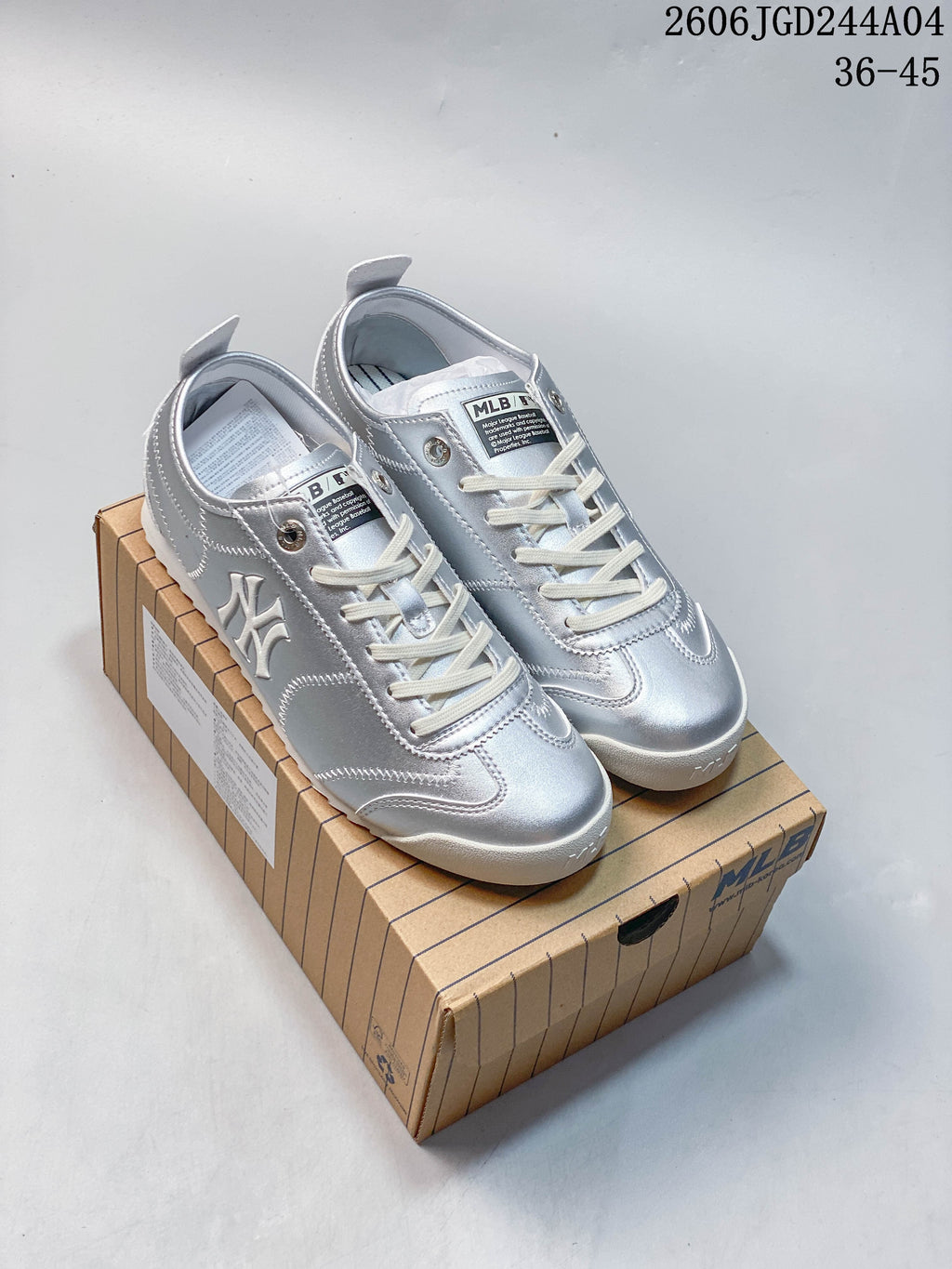 Pair of silver New York Yankees-style low-top sneakers with cream laces and white soles