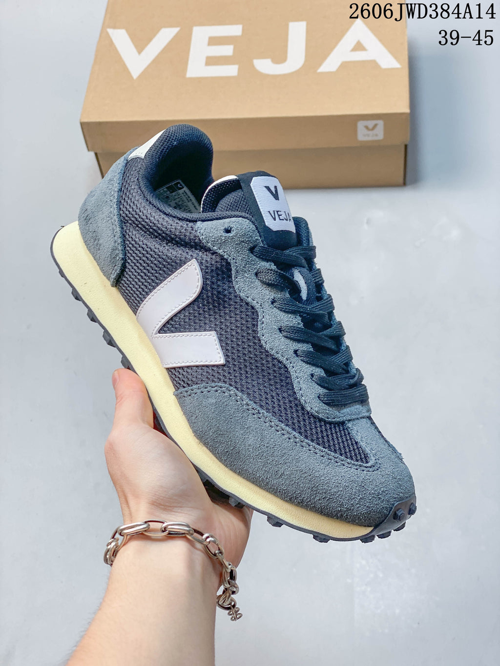 Dark navy and gray Veja sneaker with a white V-shaped side logo and cream-colored midsole.