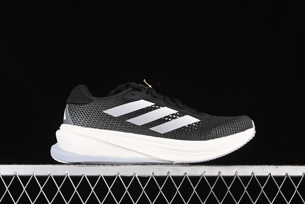 Side profile of a black running shoe with white stripes and a light-colored midsole.