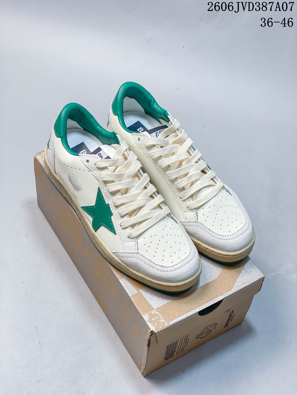 Pair of white low-top sneakers with green star and collar accents, shown on a shoe box.