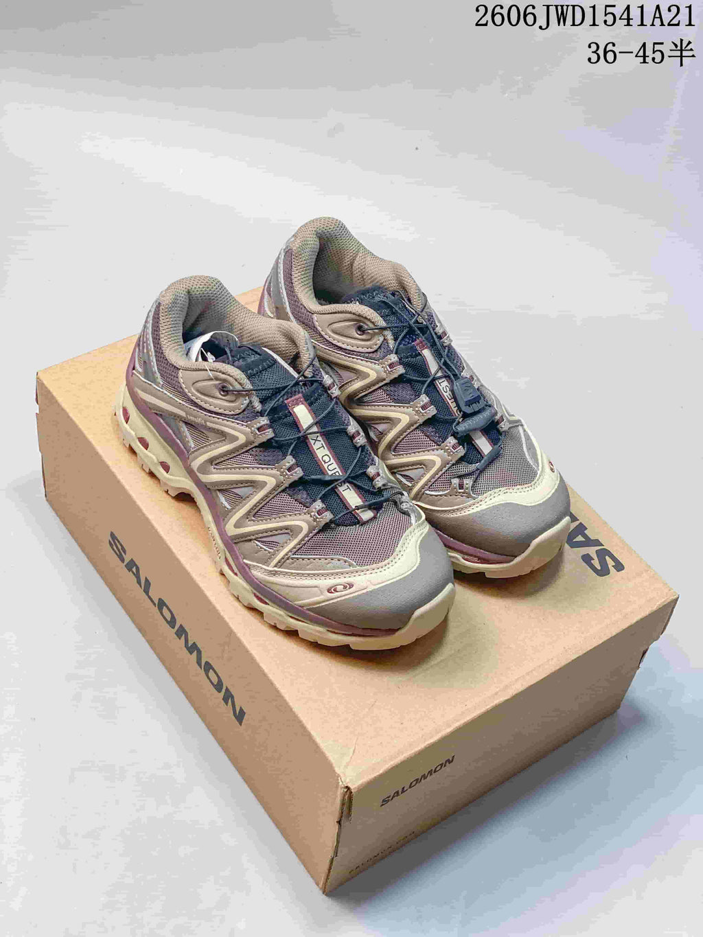 Pair of gray and mauve Salomon XT-Quest ADV shoes displayed on a branded box