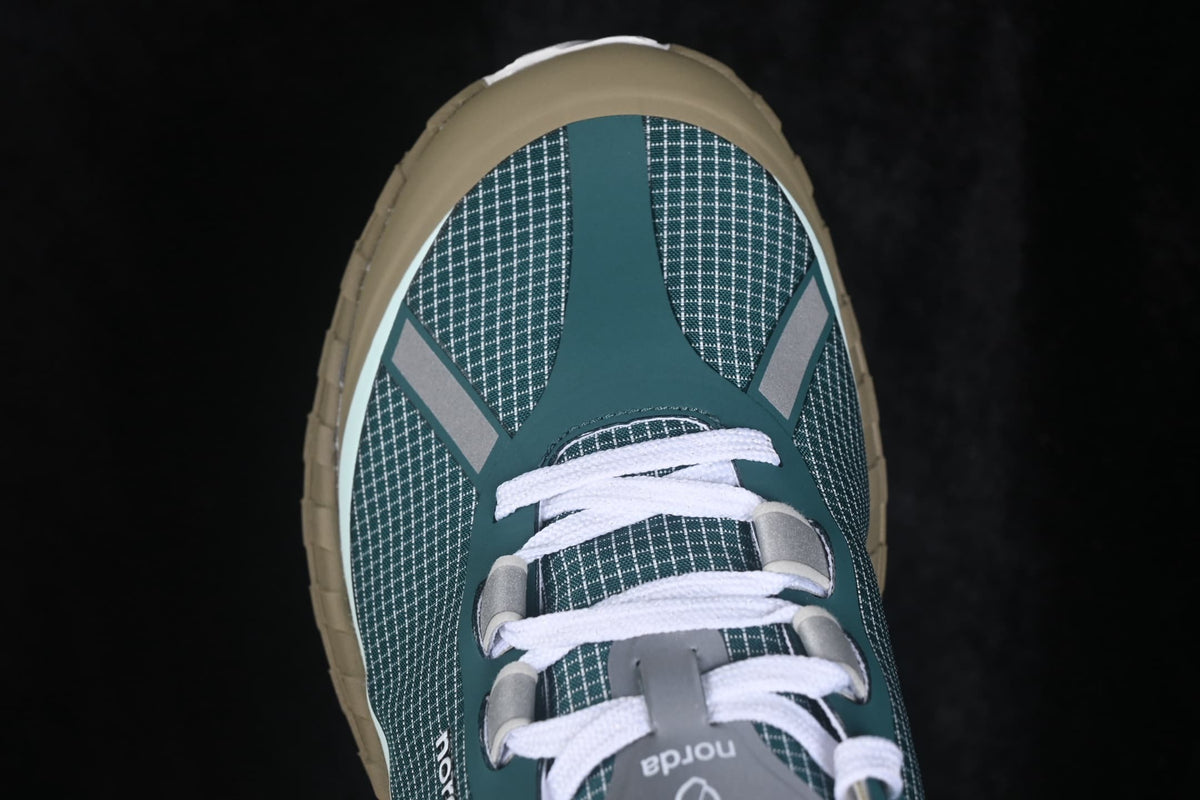 Top-down view of the patterned green sneaker upper with white laces and gray overlays.