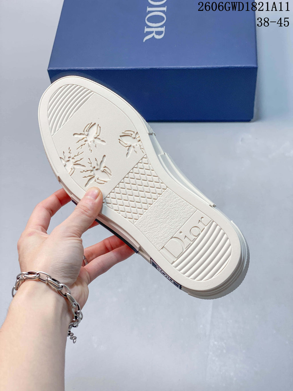Underside of a cream-colored sneaker showing patterned tread and Dior lettering