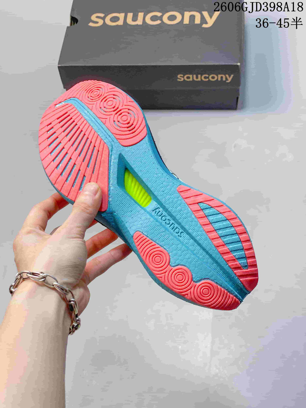 Underside view of the Saucony running shoe showing a turquoise and coral outsole