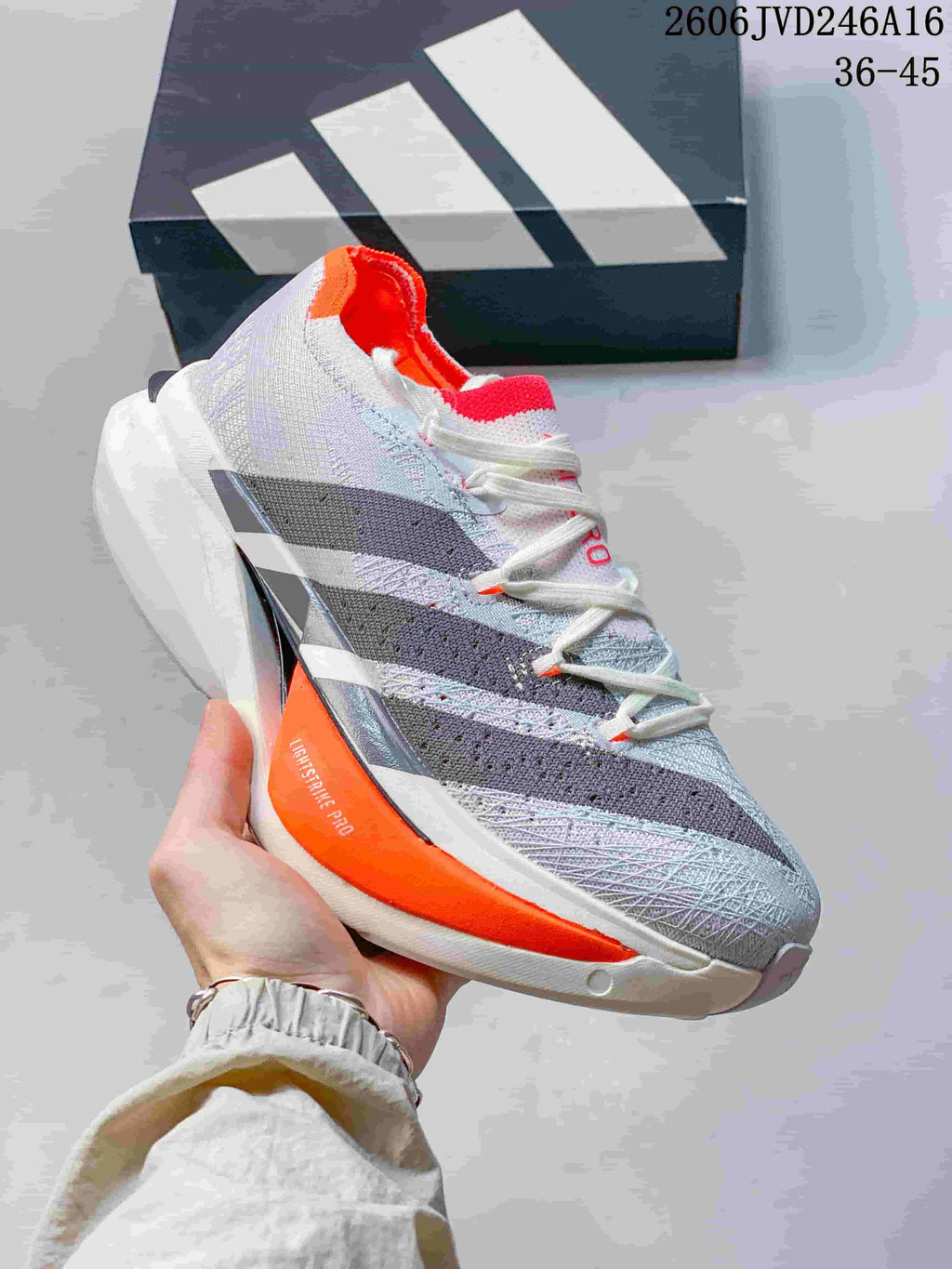 Angled side view of the shoe showing the upper, stripes and orange side accent.