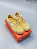 Pair of pale yellow Nike Astro Grabber sneakers with white Swooshes and off-white soles, shown on an orange shoe box.