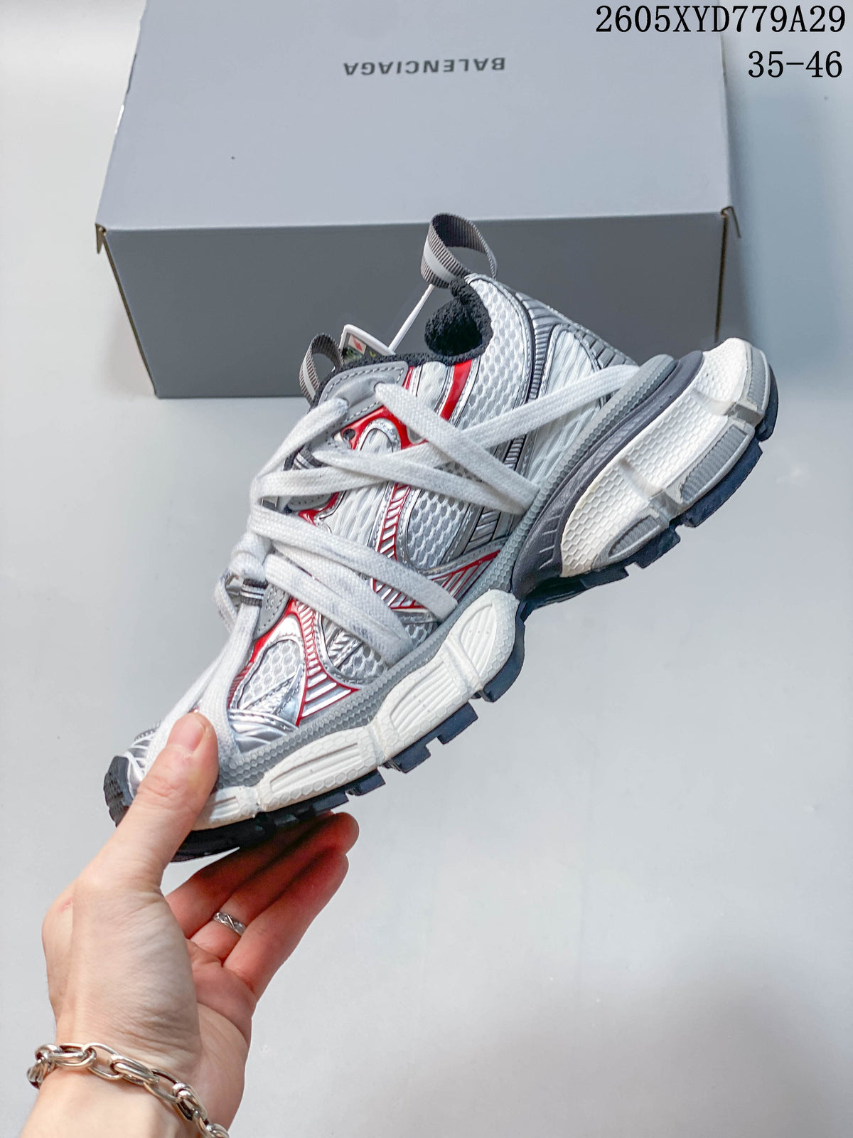 Side view of a white, silver, and red Balenciaga Phantom sneaker with layered panels and laces.