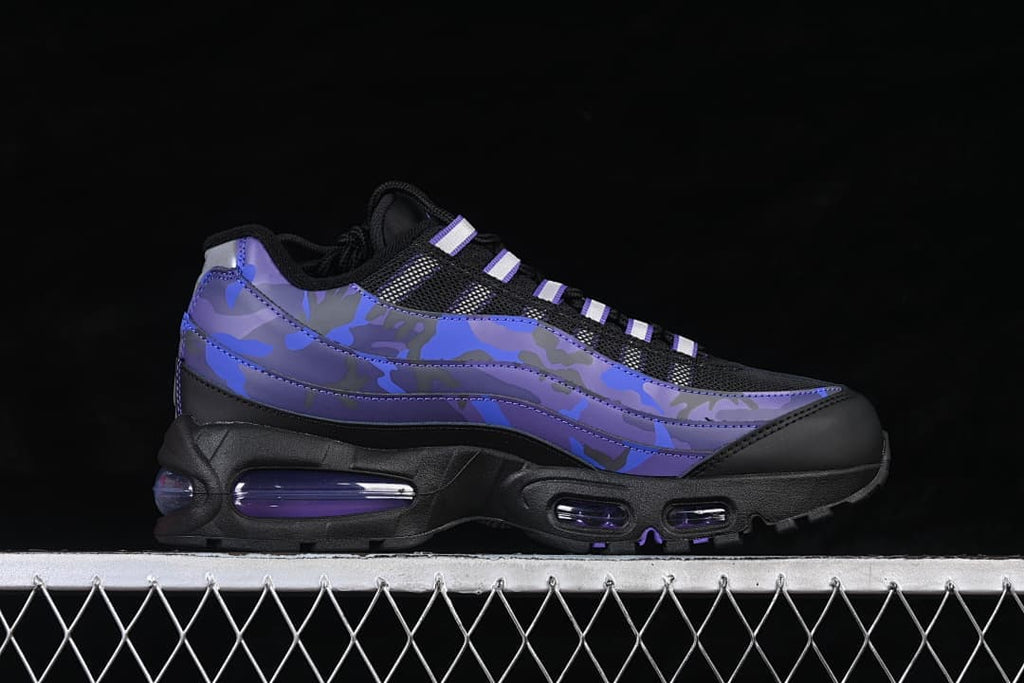 Side view of a black Nike Air Max 95 sneaker with blue and purple camouflage-style panels and visible cushioning windows