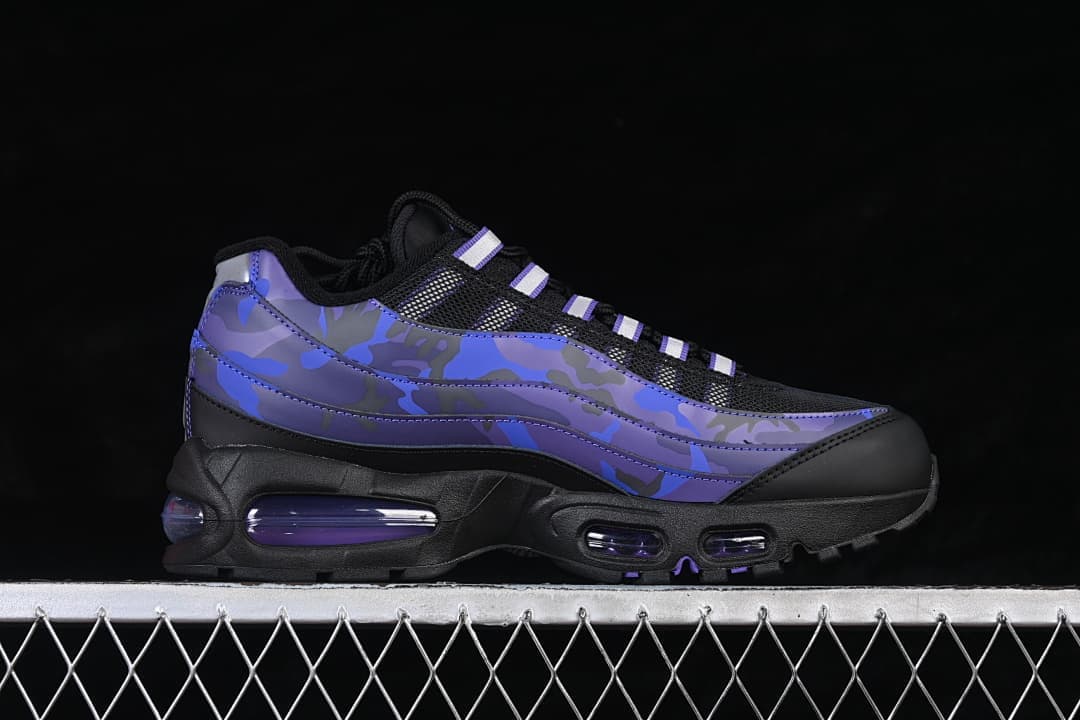 Side view of a black Nike Air Max 95 sneaker with blue and purple camouflage-style panels and visible cushioning windows