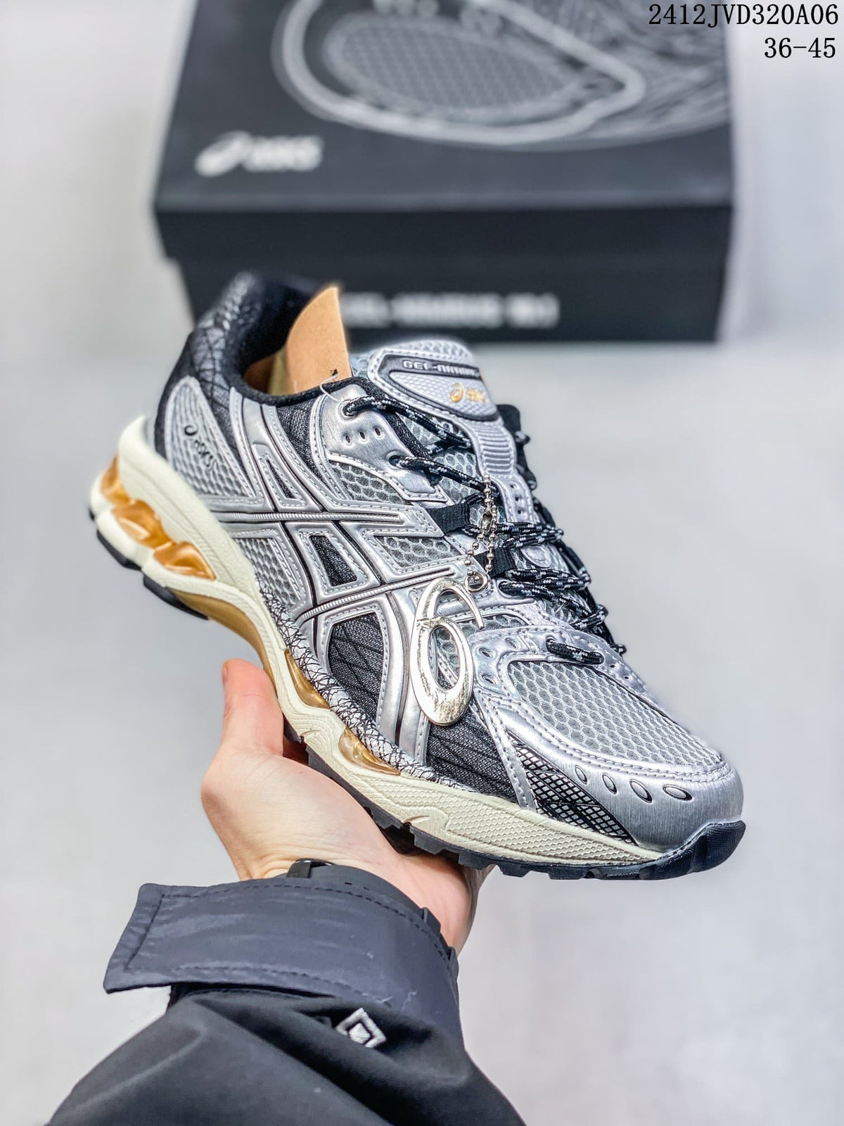 Angled view of the silver and black sneaker with side logo and amber midsole accents