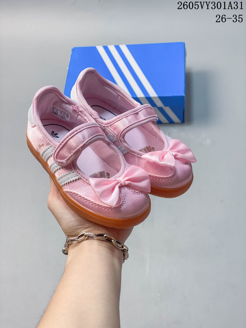 Pair of pink adidas Originals Samba Jane kids shoes with bow details, white side stripes, and gum-colored soles.