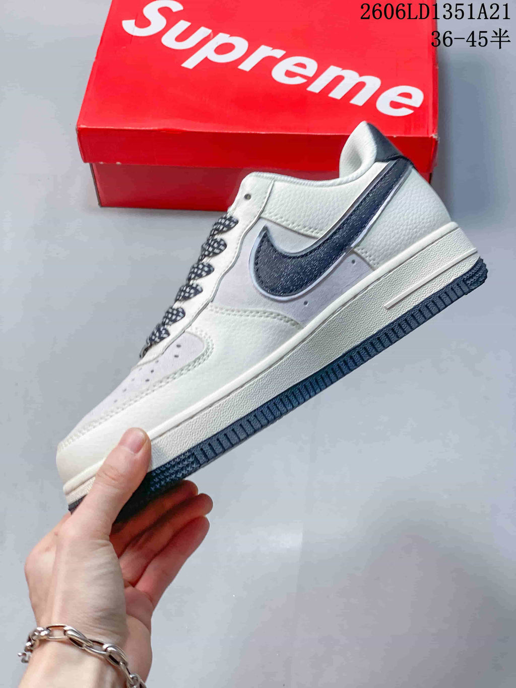 Side view of the white low-top sneaker with dark Swoosh and dark outsole.