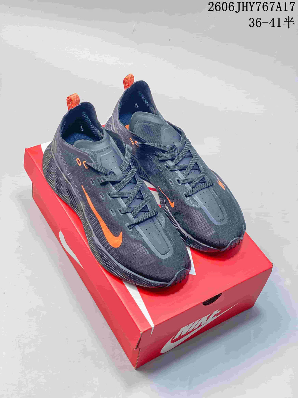 Pair of dark gray Nike Ava Rover low-top sneakers with orange accents, shown on a red shoebox.
