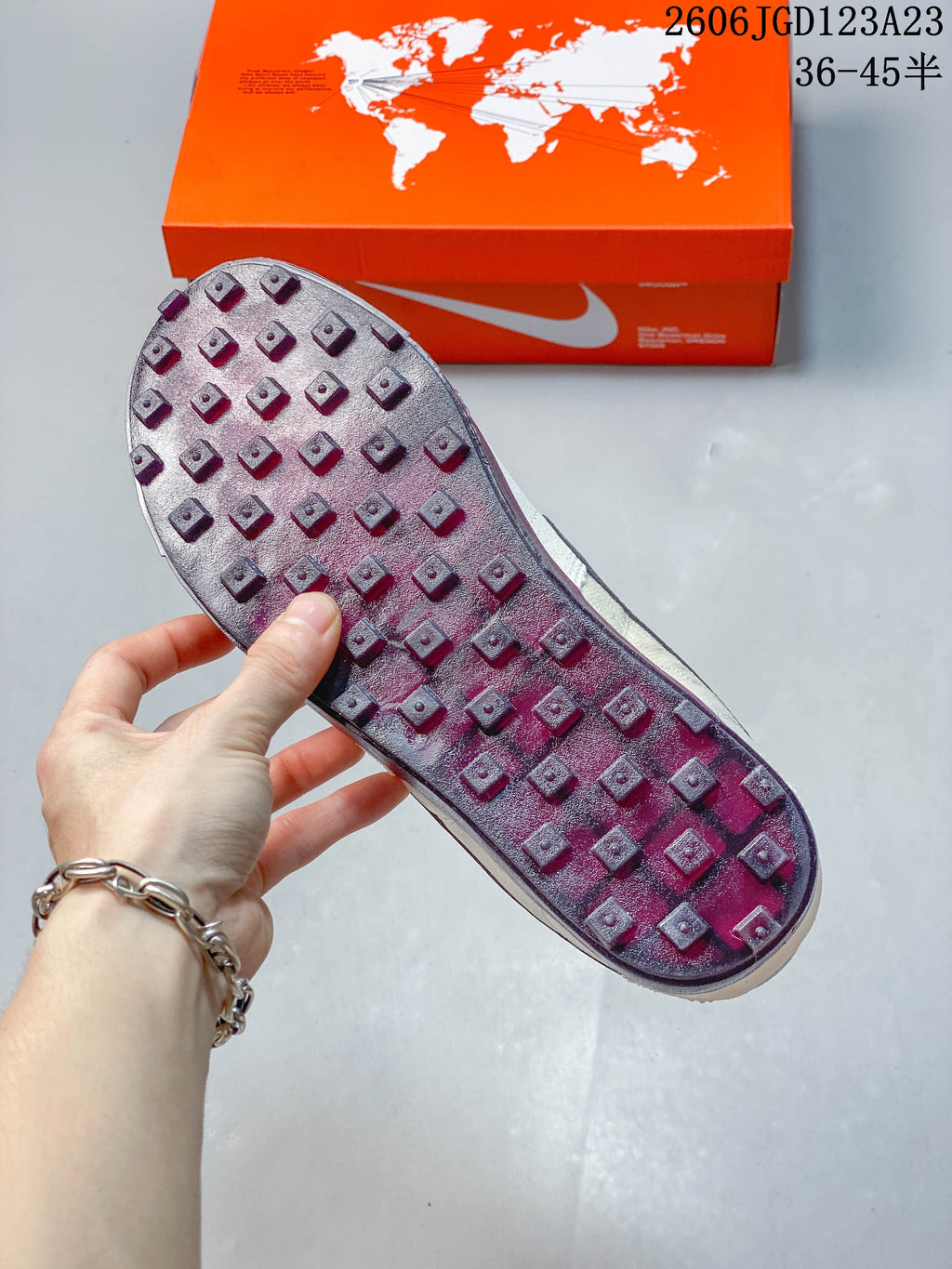 Close-up of the sneaker outsole showing raised square lugs and a plum-toned finish