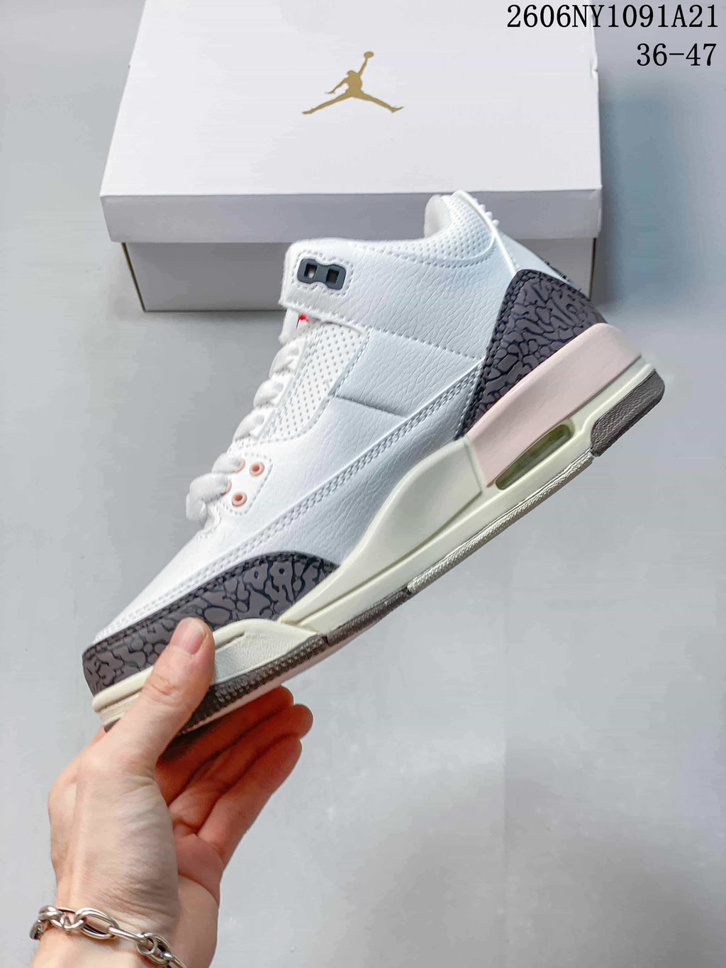Side view of the white mid-top sneaker with patterned overlays and pale pink midsole accent