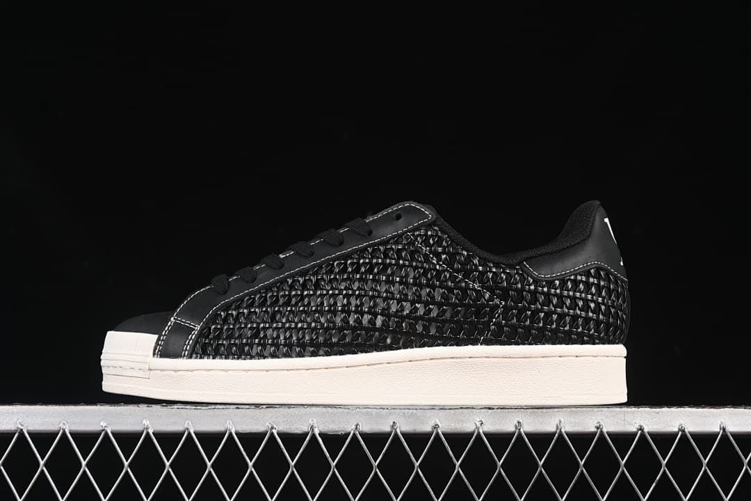 Side view of black adidas Superstar IE8878 sneakers with woven-look panels and an off-white sole