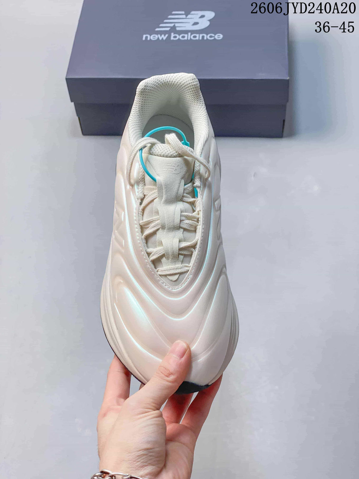 Top view of a pearl-white lace-up sneaker with padded collar and turquoise accent loop.