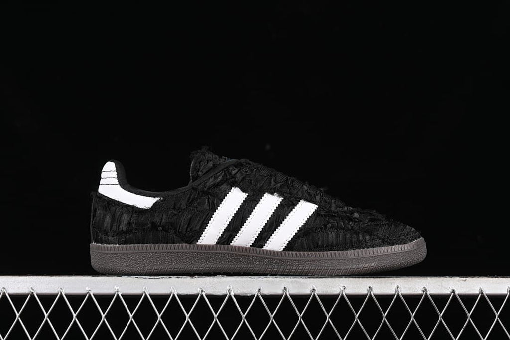 Side profile of the black sneaker with white stripes