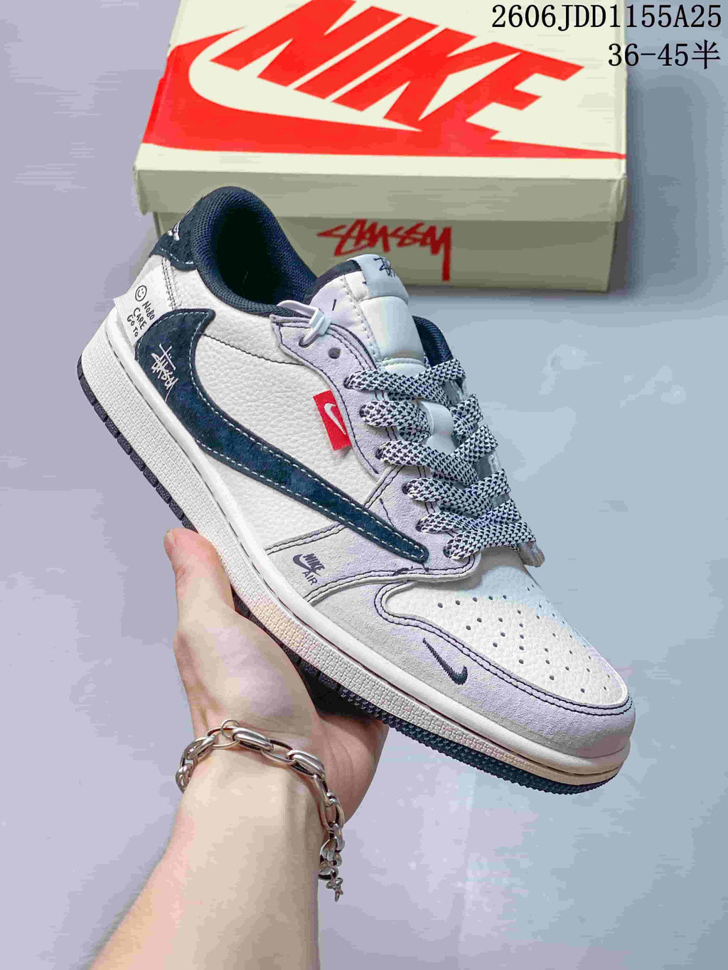 Close view of a white low-top sneaker with dark blue accents, perforated toe, and contrasting side details.