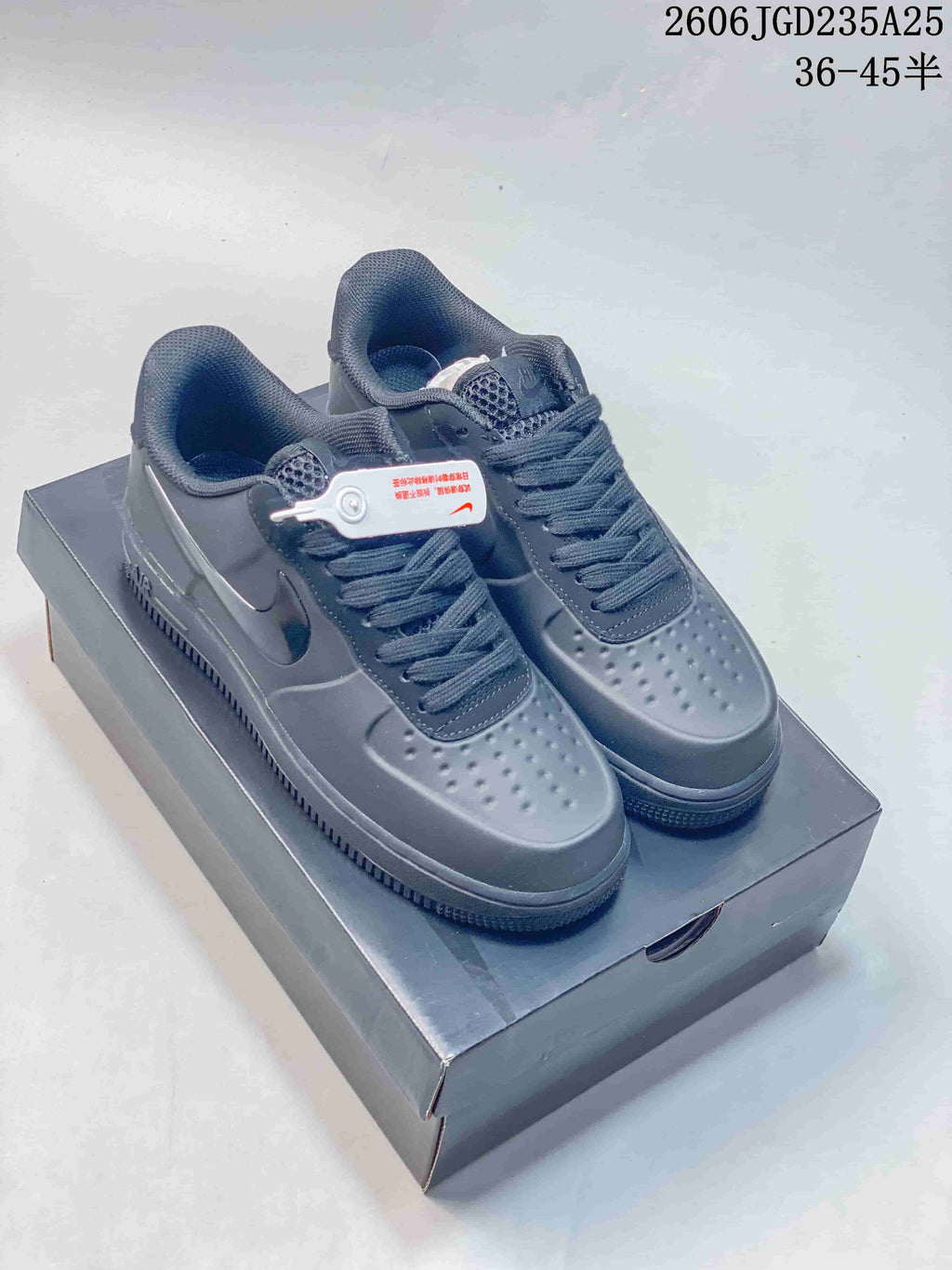 Pair of charcoal low-top lace-up sneakers with perforated toes and side Swoosh details on a dark shoe box