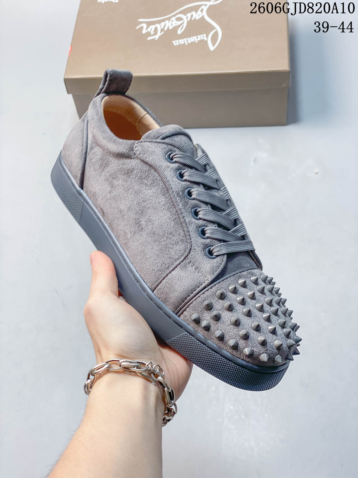 Angled view of a grey sneaker with a studded toe and textured sole