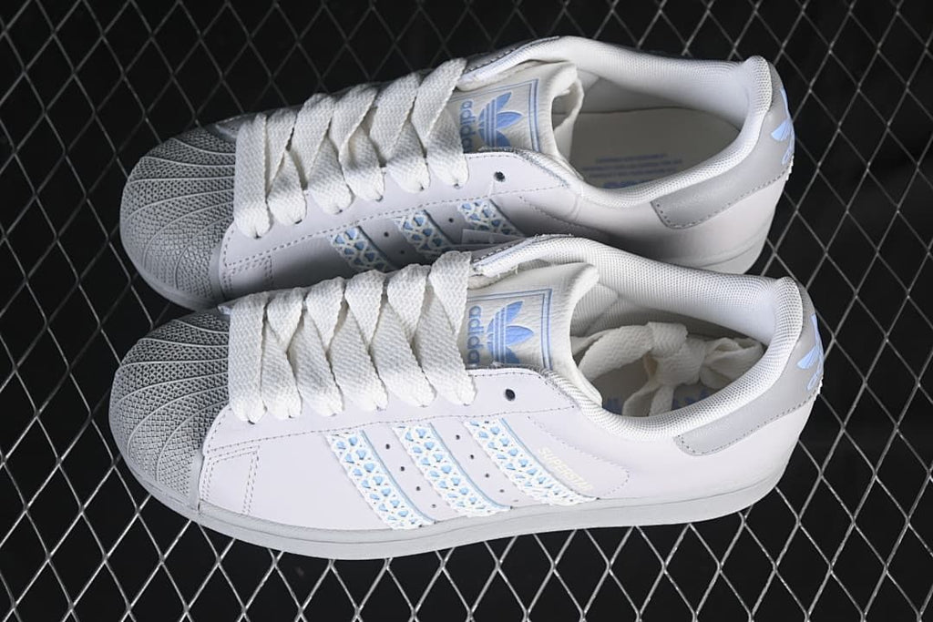 Pair of white Superstar II sneakers with pale blue accents, shown from above.