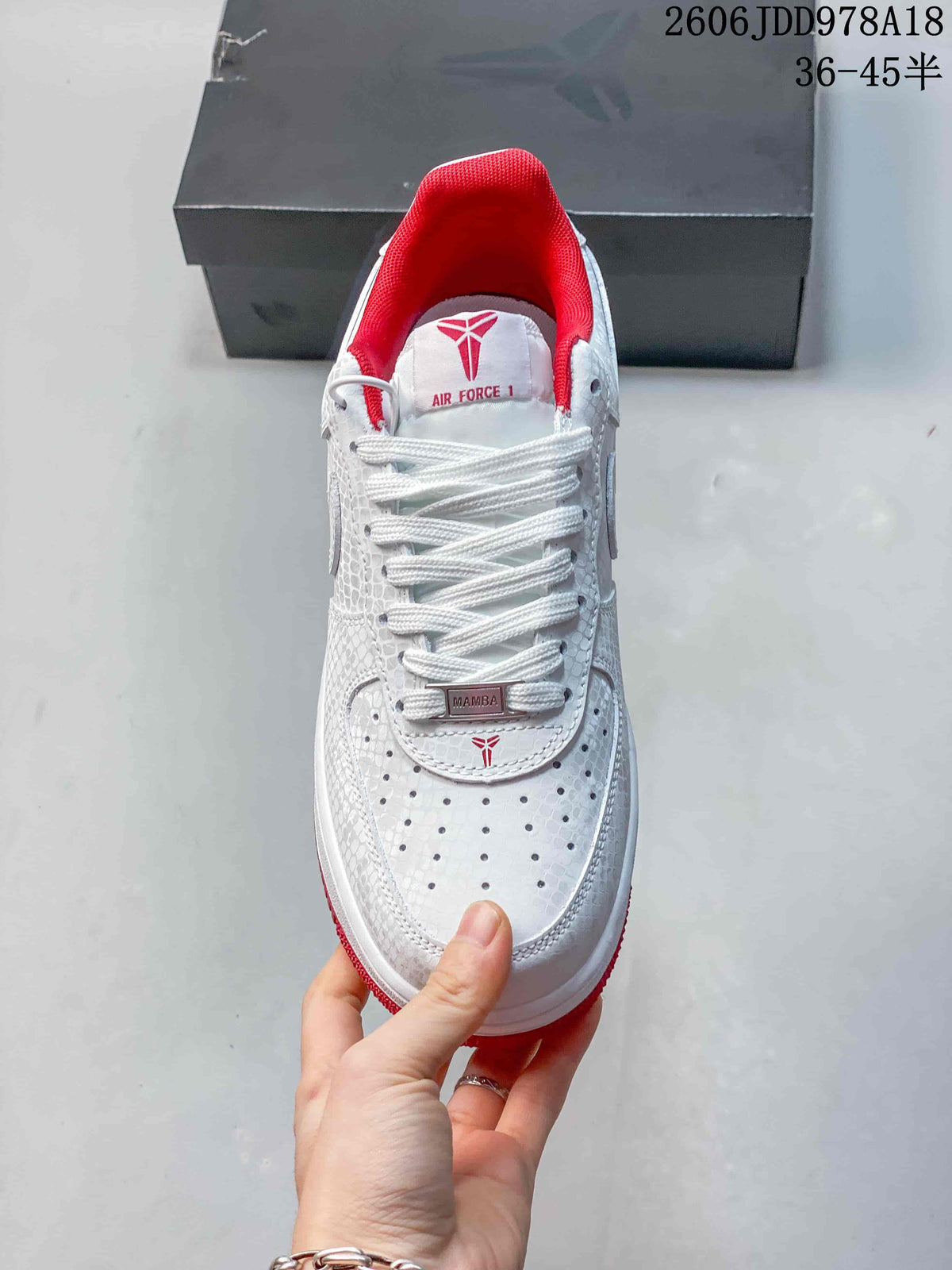 Top view of a white sneaker with red lining and Mamba-themed lace details