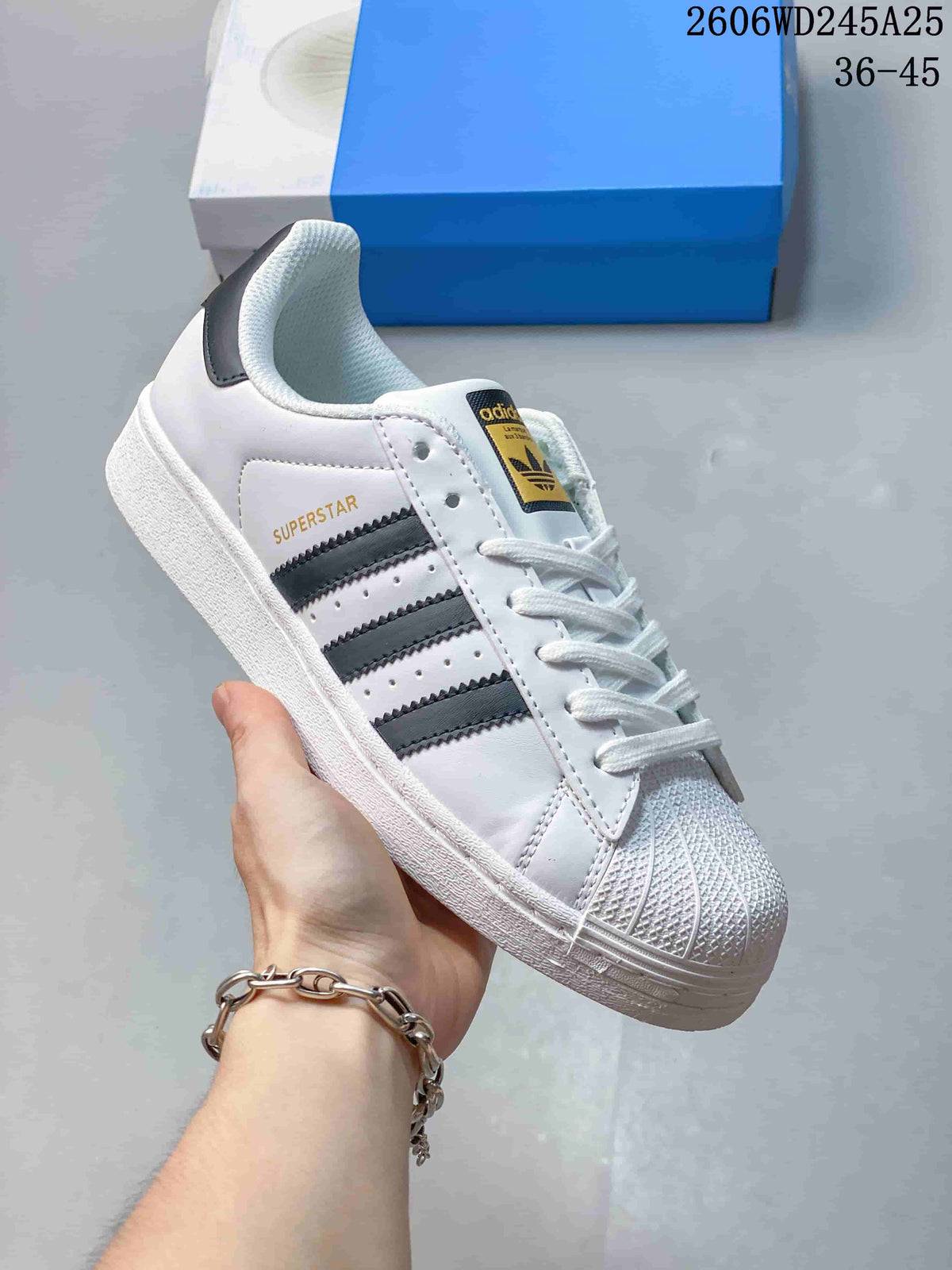 Angled side view of the white Superstar sneaker with black stripes