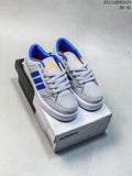 Pair of gray Adidas GVP Canvas STR sneakers with blue stripes and orange accents on a shoebox