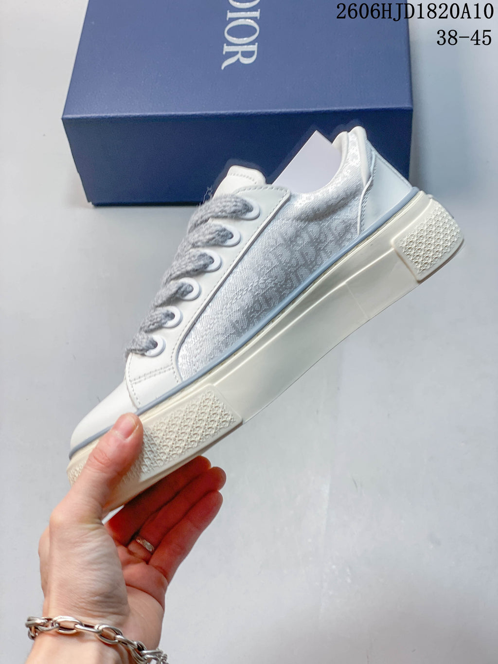 Side view of a white and gray Dior B33 low-top sneaker with patterned panels and a chunky sole