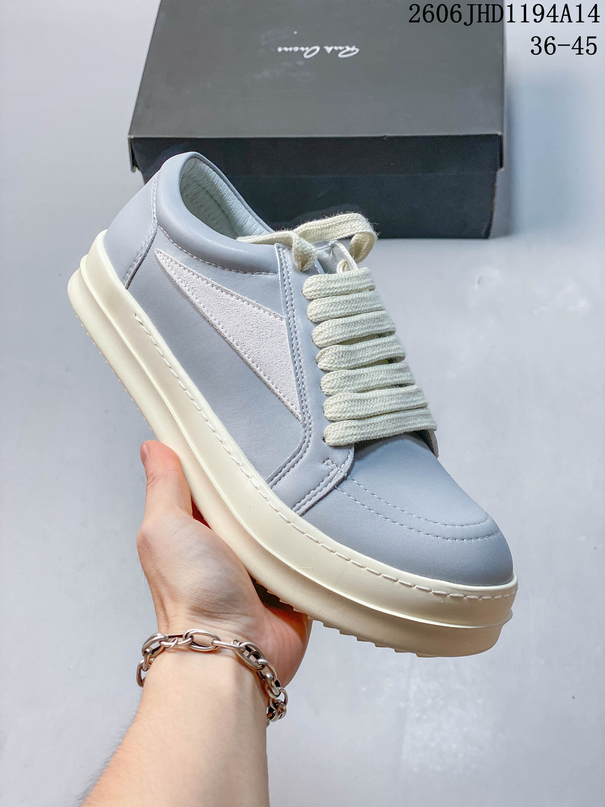 Angled side view of a pale gray low-top sneaker with a white side panel and cream laces