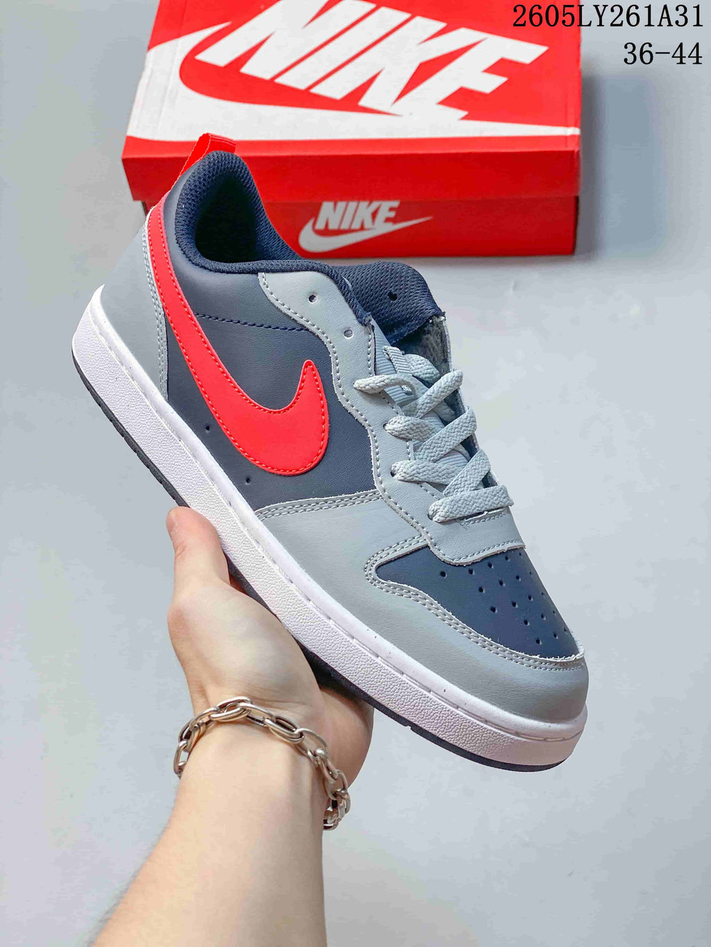 Angled side view of the navy, gray, red, and white low-top sneaker