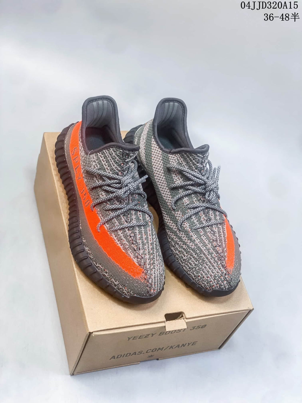 Pair of gray patterned sneakers with bright orange side stripes and dark ribbed soles.