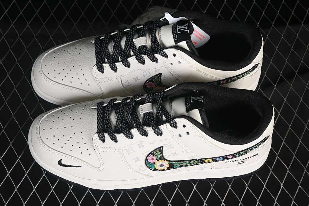 Overhead view of a pair of cream low-top sneakers showing perforated toe boxes, black laces and lining, patterned panels, and floral side embroidery.
