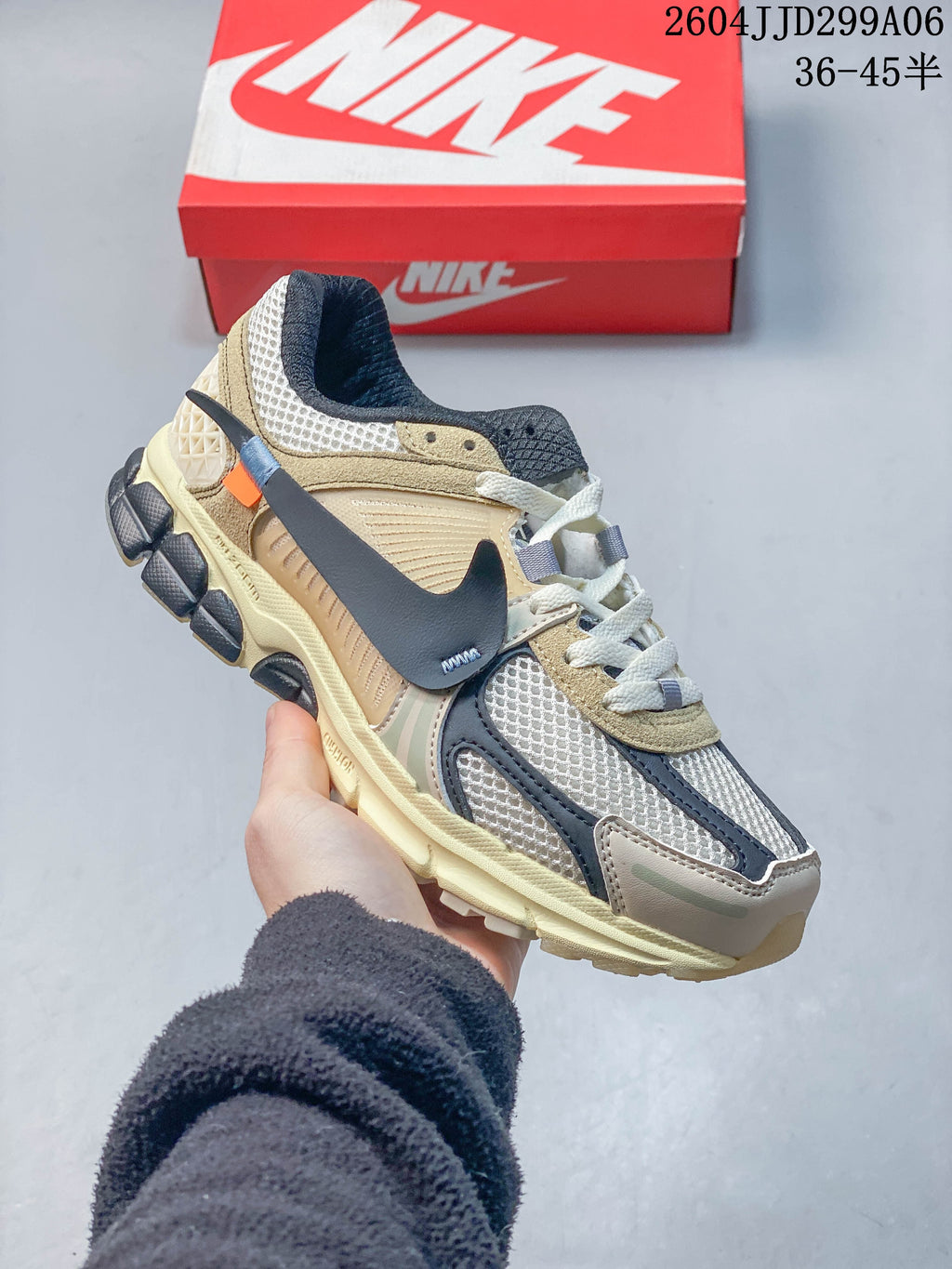 Angled side view of a beige and dark gray Nike Zoom Vomero 5 sneaker.