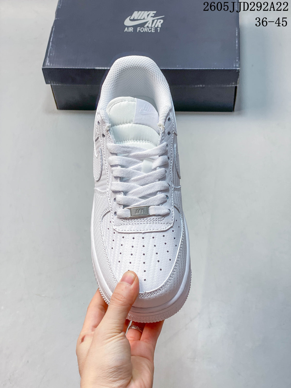 Front view of a white lace-up sneaker with a perforated toe