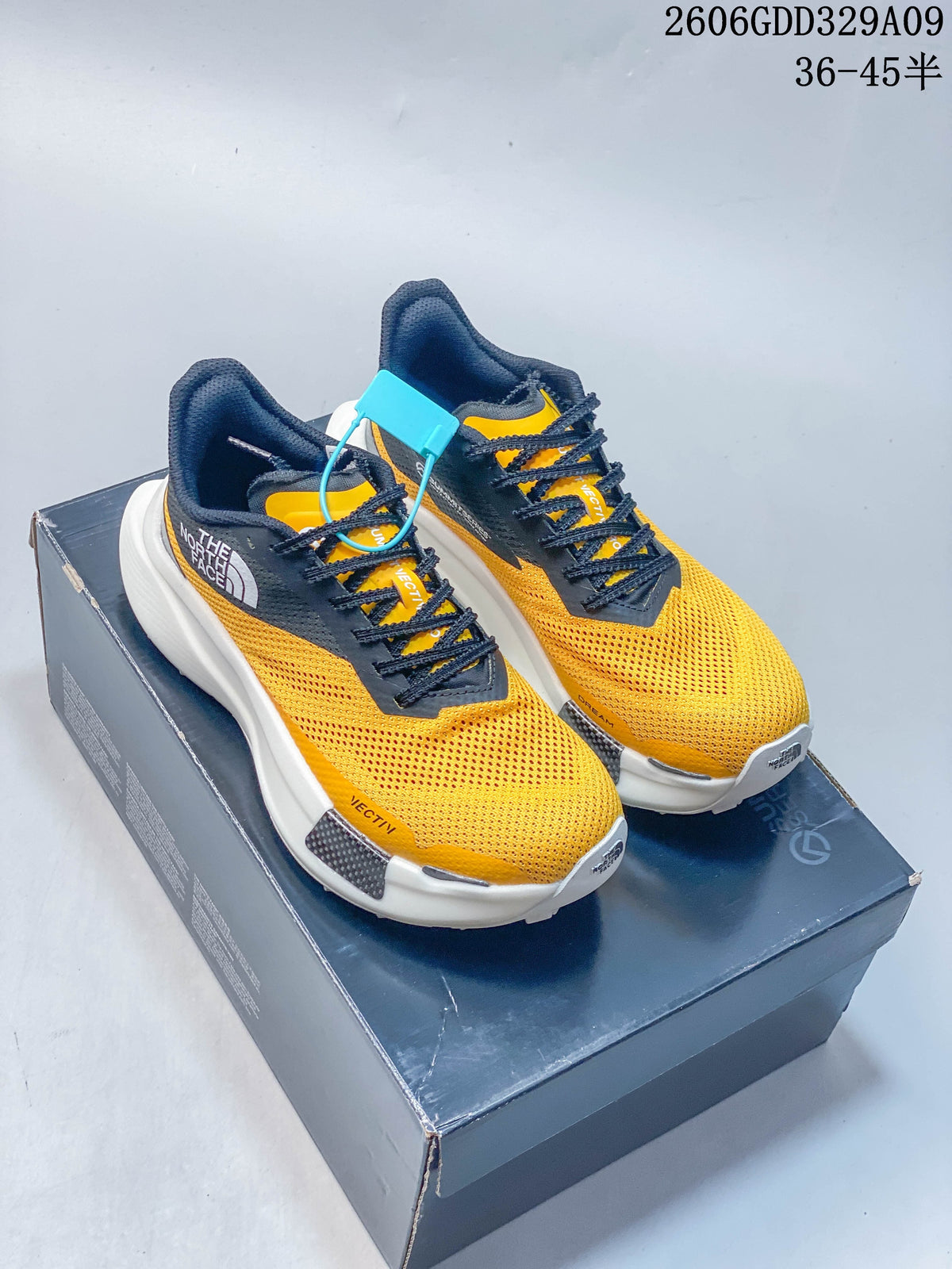 Pair of yellow and dark gray The North Face VECTIV hiking shoes displayed on a shoe box.
