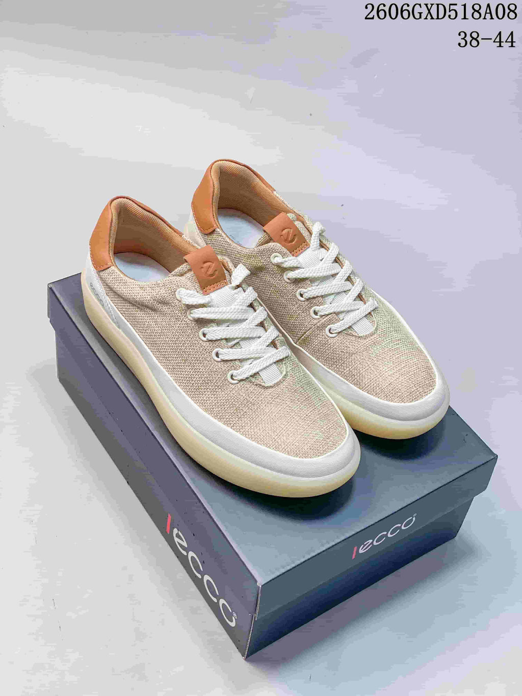 Pair of beige ECCO lace-up sneakers with white trim and tan heel accents, shown on a branded box.