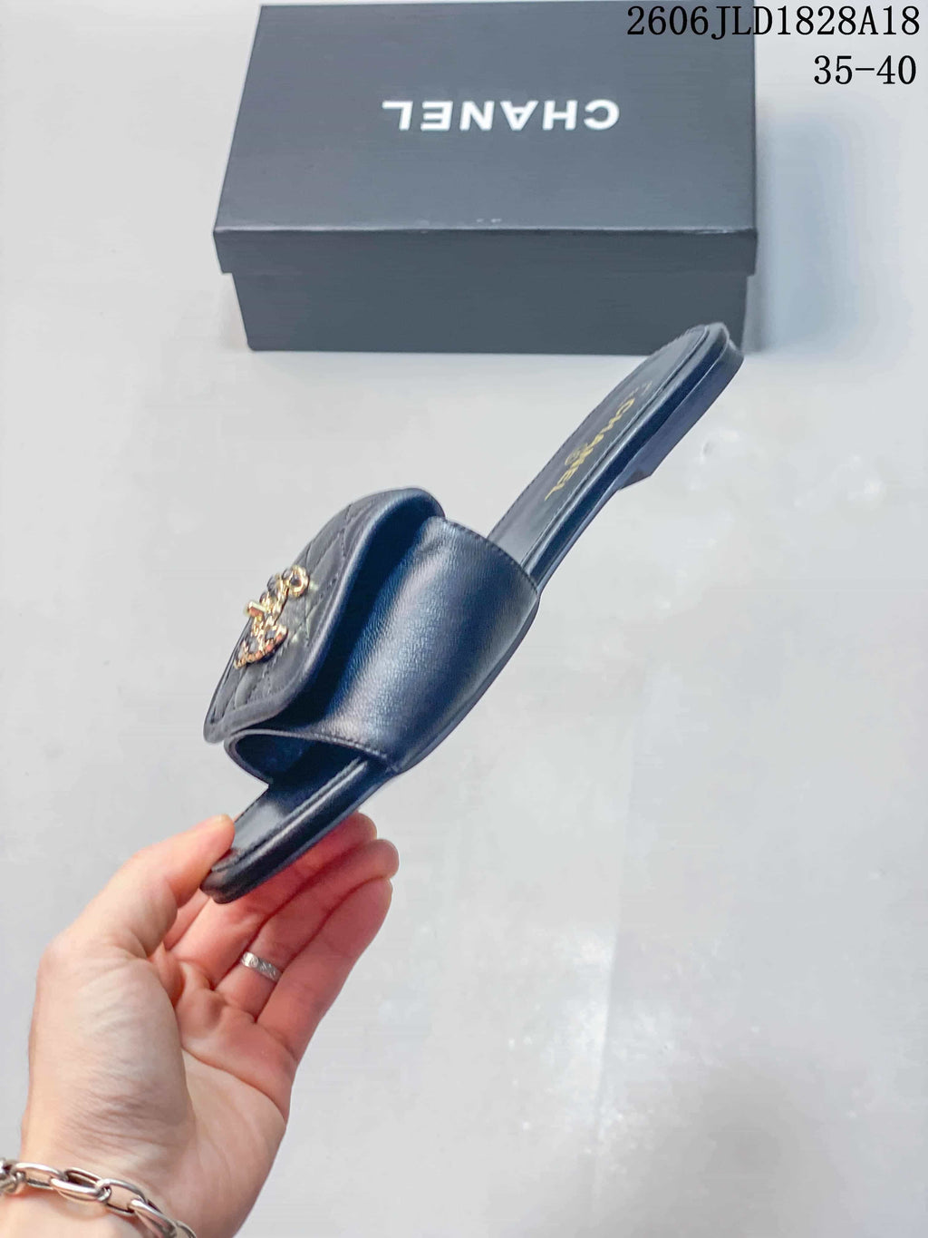 Side profile of a navy slide sandal with a quilted strap and ornament