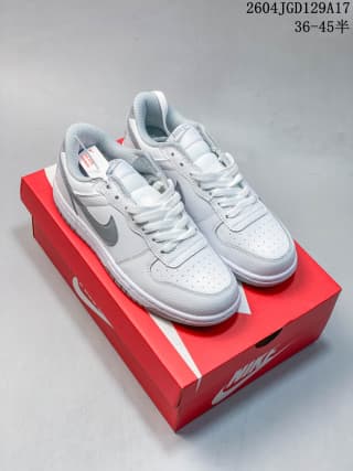 Pair of white low-top Nike sneakers with light gray Swoosh accents displayed on a red Nike shoe box.