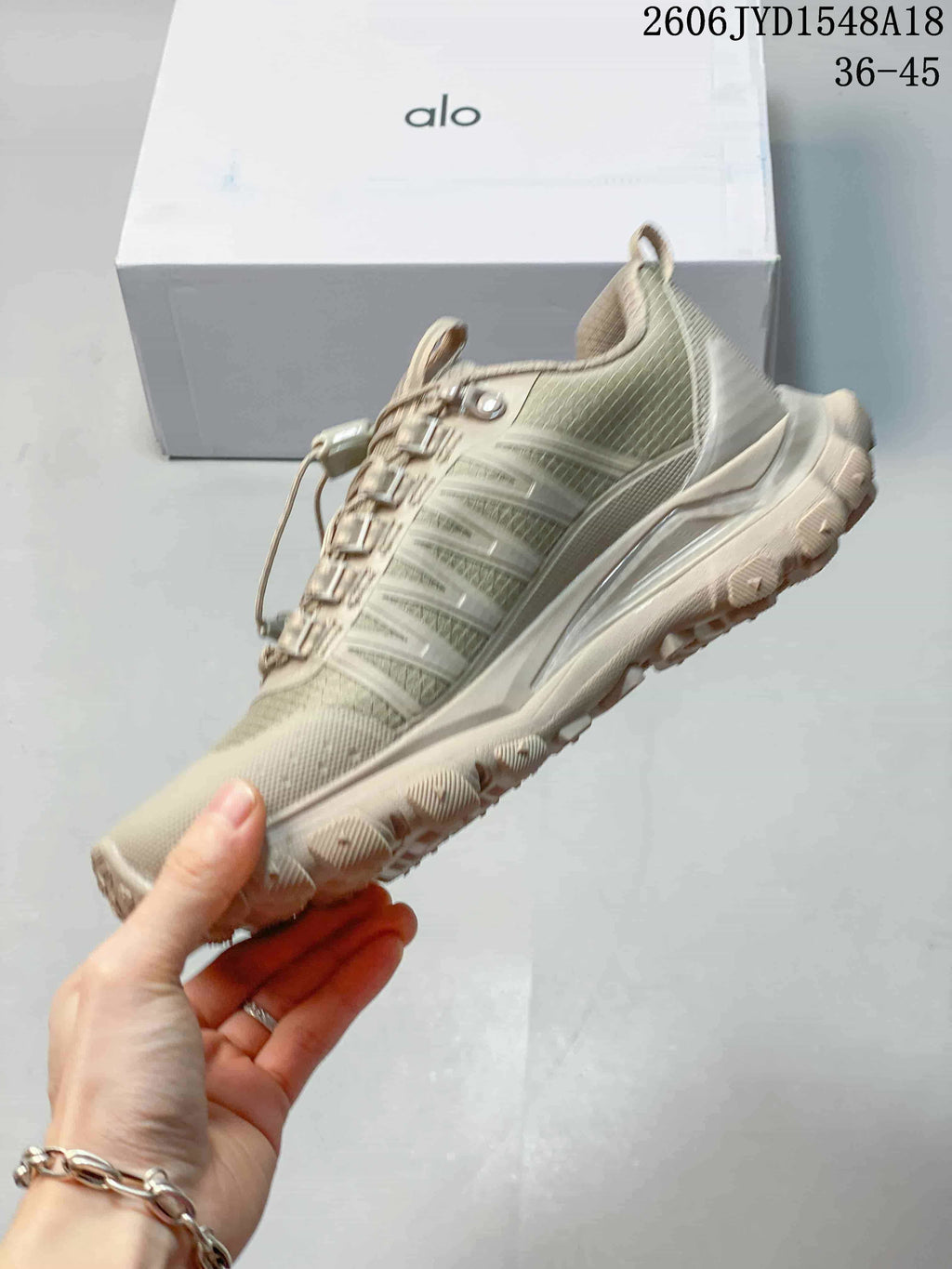 Side profile of a taupe trail shoe with quick-lace fastening.
