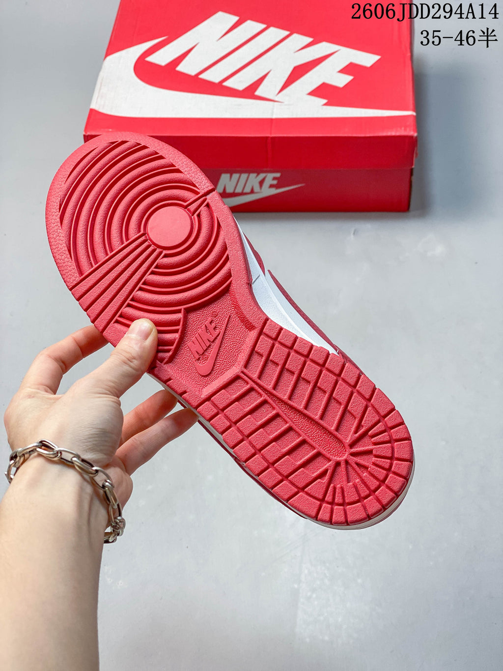 Red outsole of a Nike Dunk Low sneaker with the shoe box in the background.