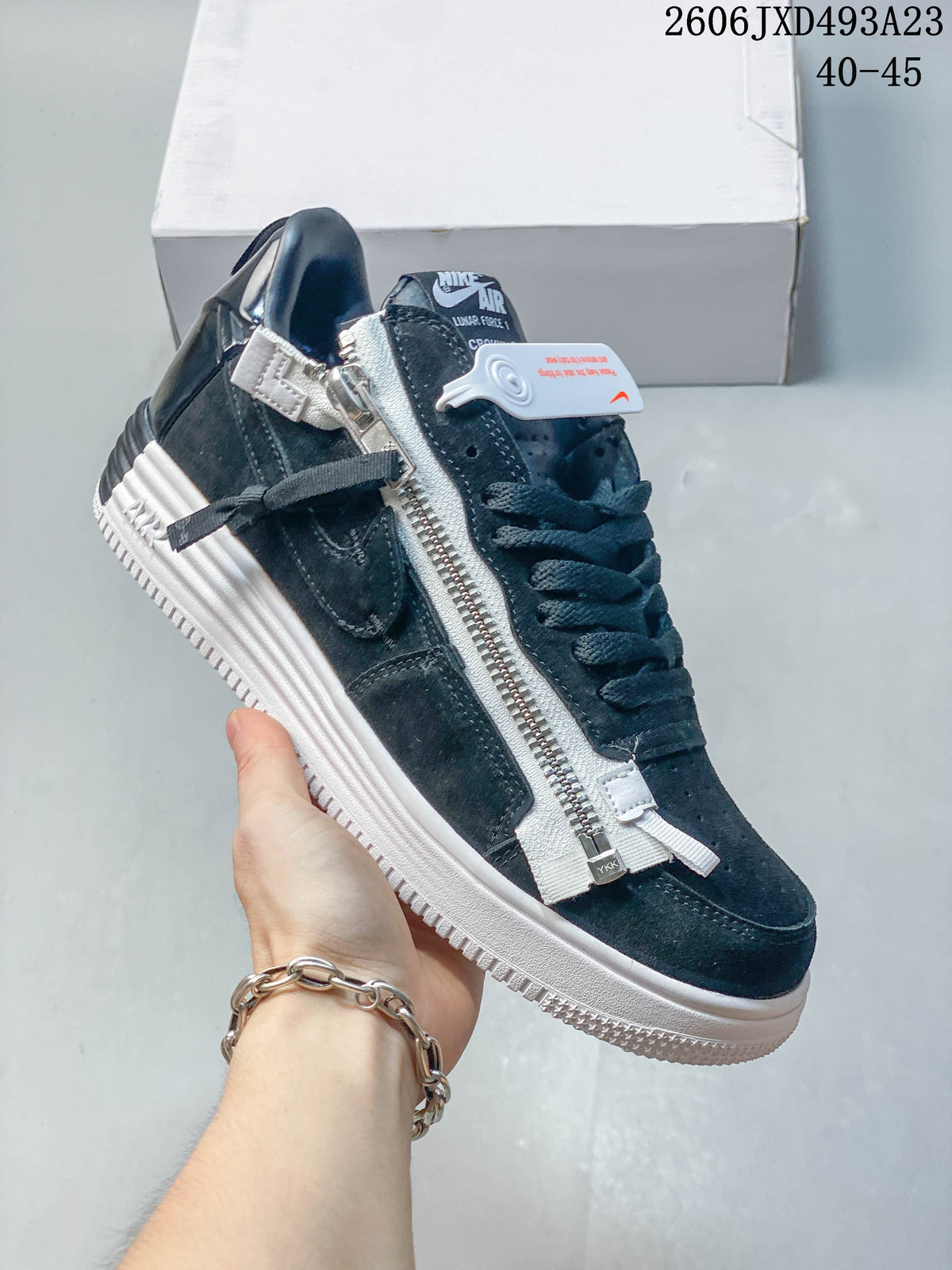 Angled view of the dark sneaker highlighting the long side zipper and white sole.