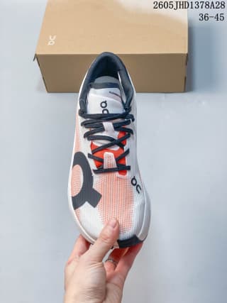 Top view of the white and coral On Cloudboom Volt with dark laces.
