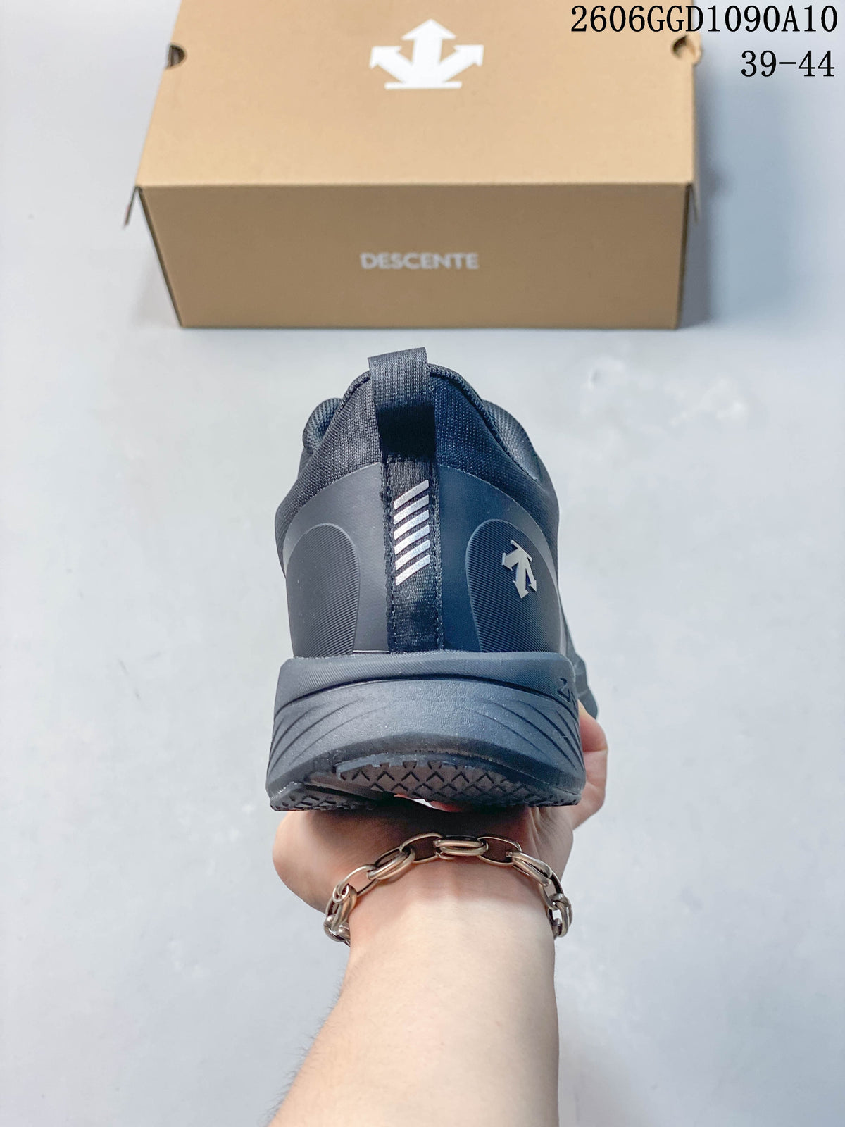 Rear view of a dark gray Descente sneaker with heel pull tab and logo; image text lists sizes 39–44.