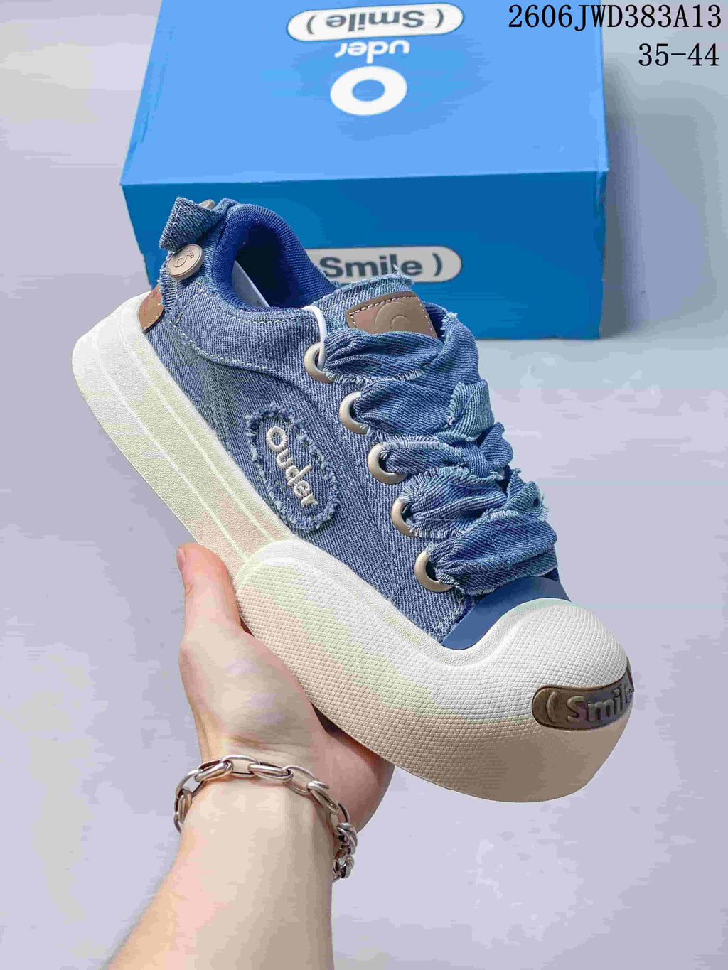 Angled view of a blue denim Ocai Smile sneaker with a white sole and oversized laces.