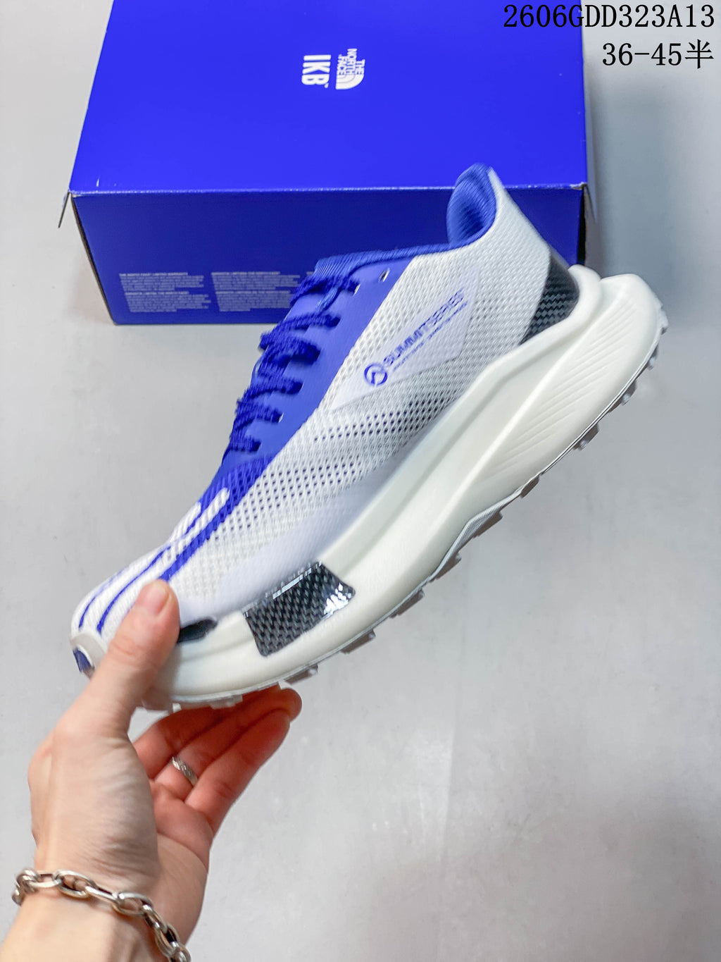 Side view of the gray-and-white shoe with blue details and a thick midsole