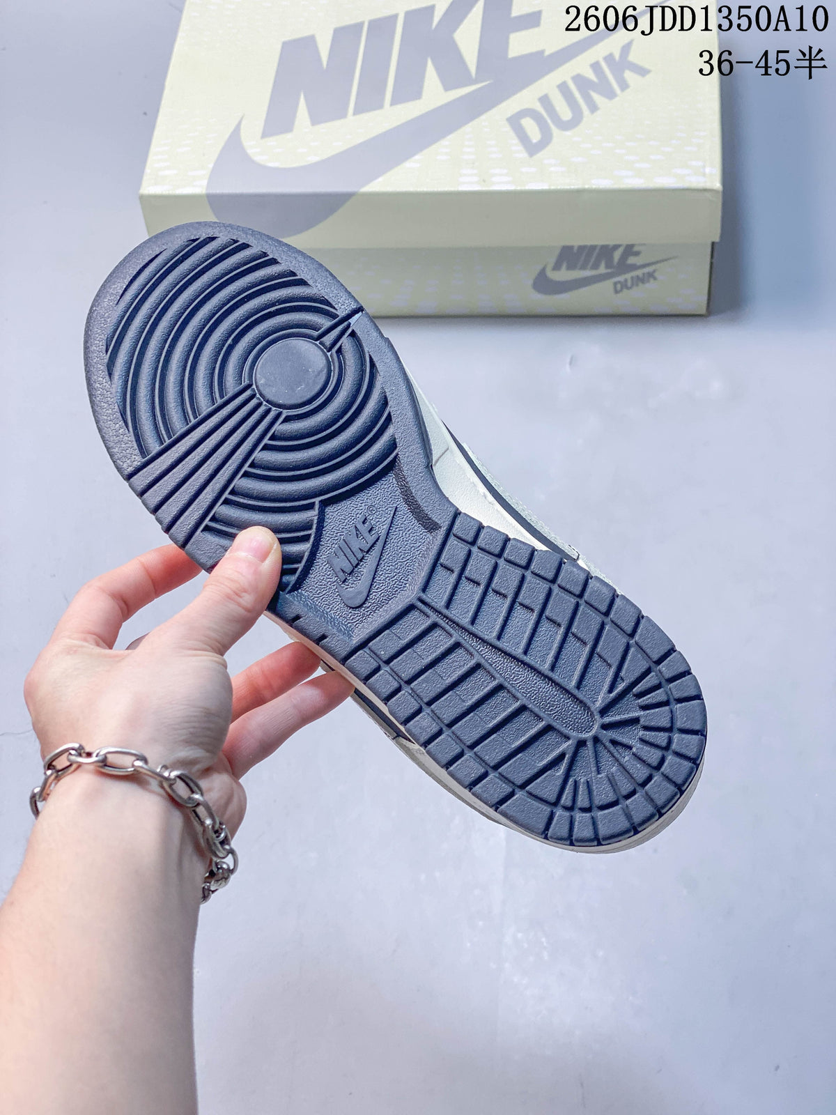 Navy rubber outsole shown beneath the sneaker, with a Nike Dunk shoebox behind it